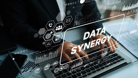 Business Professional Working on Laptop with Data Synergy Graphics Displayed on Screen in Modern Office Environment. Asymptotic smart data analytic.の写真素材