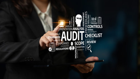 A business professional interacts with a digital tablet showcasing key audit terms, emphasizing the importance of compliance, documentation, and analysis in effective financial oversight. Tesselの写真素材