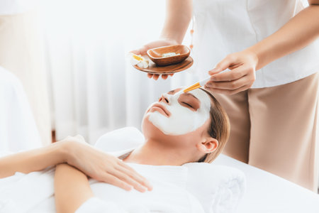 Serene ambiance of spa salon, woman customer indulges in rejuvenating with luxurious face cream massage with modern daylight. Facial skin treatment and beauty care concept. Quiescentの写真素材