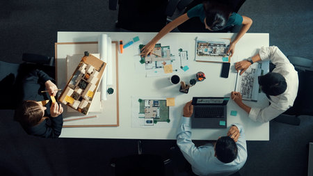 Group of diverse team planning strategy while sitting at table with project plan. Top aerial view of...