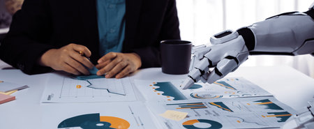 A modern business meeting featuring a human and a robot discussing financial data. The collaborative atmosphere emphasizes technology's role in data analysis and decision-making.の写真素材