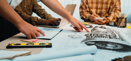 A dynamic team collaborates in a bright office, surrounded by engineering plans and various tools. Laptops and documents facilitate a productive brainstorming session.の写真素材