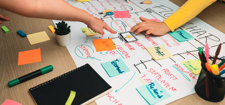 A vibrant workspace scene showcasing diverse hands pointing at a flowchart adorned with colorful...