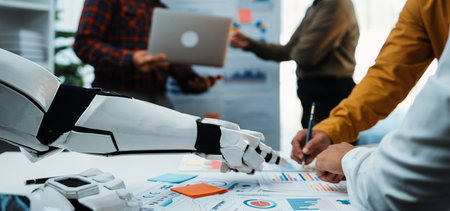 A modern office scene showcasing a robot assistant engaging with professionals who discuss documents, laptops, and data analysis in a collaborative environment.の写真素材