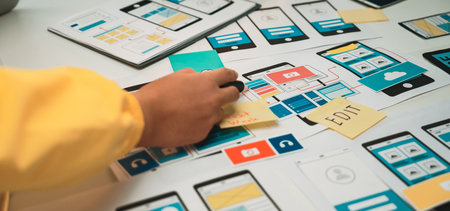 A close-up view of a hands-on mobile app design process featuring colorful sketches, notes, and...