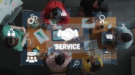 A diverse team collaborates around a table, utilizing technology and visual aids, highlighting the importance of service and cooperation in achieving business goals. Rasterの写真素材