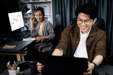 Smiling businesswoman trader with partner discussing on stock market trading exchange in casual suit, getting highest profit trading value financial technology investment at office at night. Infobahn.の写真素材
