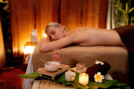 Woman customer having exfoliation treatment in luxury spa salon with warmth candle light ambient....