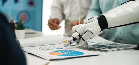 A robotic hand points to business charts in a modern office setting, showcasing the intersection of...