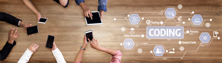 Engaging overhead view of hands using devices for coding and programming on a wooden table,...