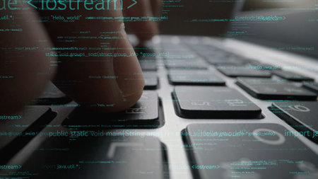This close-up image captures fingers typing on a laptop keyboard, with digital code overlay that...