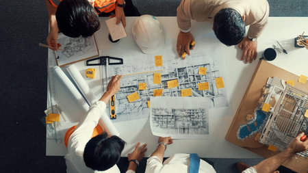 Top down view of skilled engineer team compare between blueprint and house plan. Aerial view of...
