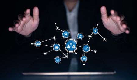 A businessperson uses hand gestures over a digital screen displaying abstract icons, representing...