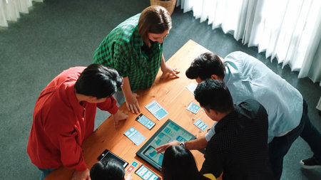 Top view of diverse business people discussing idea and designing system while using tablet with Ux,...
