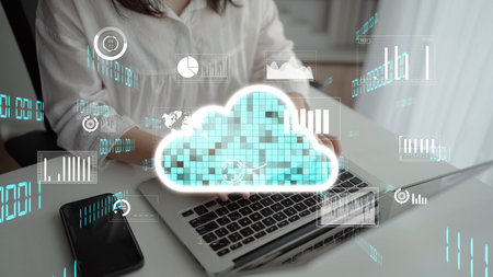 A person engages with a laptop showcasing cloud computing and digital charts, illustrating modern...