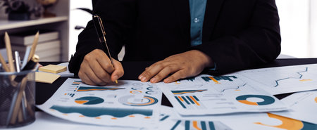 A business professional engaged in a detailed analysis of financial reports and graphs at a modern...