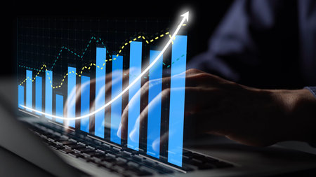 A close-up of a person's hands typing on a laptop, showcasing a digital display of financial growth...