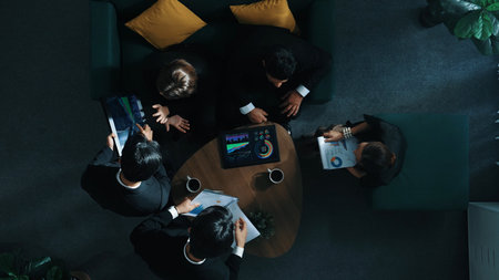 Top down aerial view of business people working together to plan marketing strategy while looking at...
