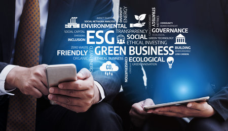 Two business professionals focus on mobile devices, exploring ESG concepts in a modern corporate...