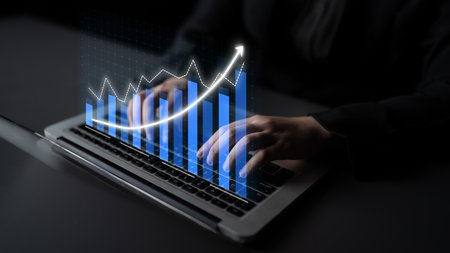 A professional examines financial data on a sleek laptop, showcasing a digital graph that symbolizes...