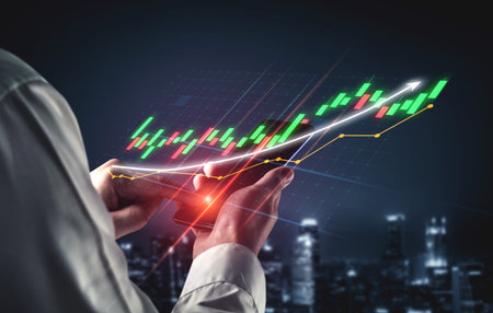 A business professional reviews financial data on their smartphone, featuring vibrant graphs and...