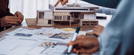 A collaborative design session featuring a scale model of a modern building, architectural...