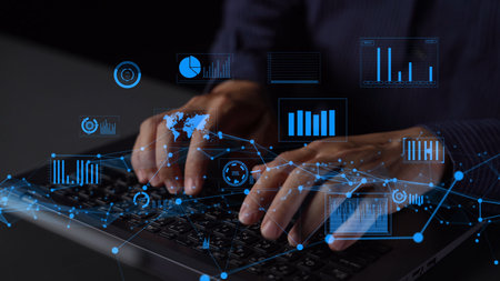 A close-up view of hands typing on a keyboard, surrounded by digital data overlays featuring various...