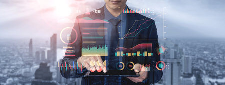 A business professional focuses on data and financial graphs displayed on a digital tablet, set...