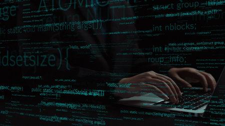 Close-up of hands typing on a laptop, with a backdrop of code lines illustrating programming...