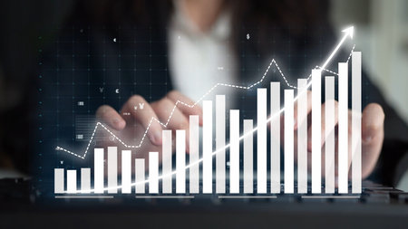 Business professional analyzing data trends with digital graph overlaid on keyboard in office...