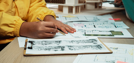 Hands engaged in sketching architectural plans on paper, showcasing a vibrant collaborative...