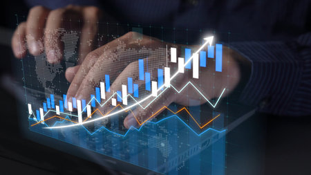 Hands engaged in typing on a laptop with overlaid digital graphs and charts, symbolizing financial...
