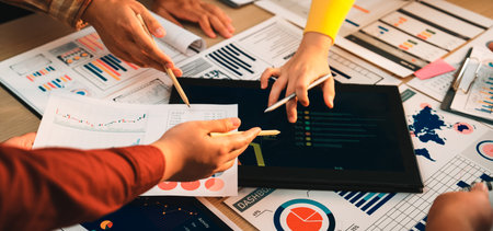 Engaging business meeting scene featuring hands analyzing data on a tablet alongside colorful charts...
