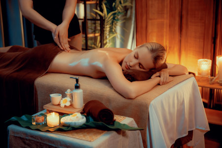 Caucasian woman customer enjoying relaxing anti-stress spa massage and pampering with beauty skin recreation leisure in warm candle lighting ambient salon spa at luxury resort or hotel. Quiescentの写真素材
