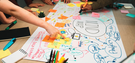 Groups of diverse hands engage in a lively brainstorming session, creating a vibrant mind map on a...