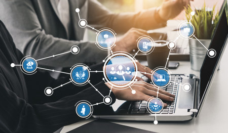 Business professionals collaborate at a modern workspace, utilizing a laptop with visual network...