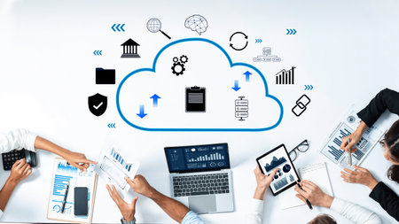 Professionals collaborate around a table using digital devices, discussing cloud technology while...