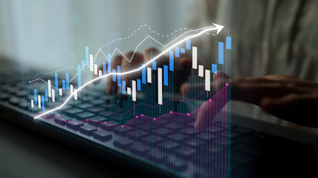A close-up view of hands typing on a laptop keyboard with an overlaid financial graph showcasing...