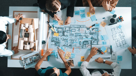 Top aerial view of manager shaking hand and making contract at meeting table with blueprint and house model. Group of diverse people working together and celebrate successful project.の写真素材