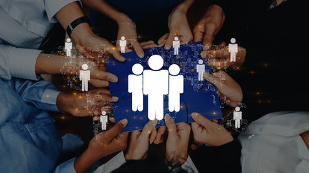 A diverse group of hands collectively holds a blue background featuring digital icons representing...