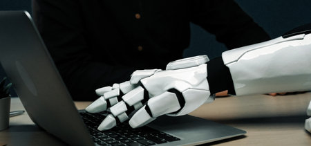 A robotic hand engages with a laptop, representing the convergence of technology and human...