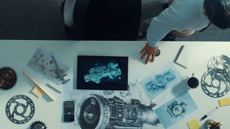 Top down aerial view of smart engineer calling manager about turbine engine structure while looking...