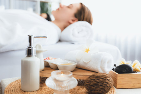 Aromatherapy massage on daylight ambiance or spa salon composition setup with focus decor and spa accessories on blur woman enjoying blissful aroma spa massage in resort or hotel background. Quiescentの写真素材