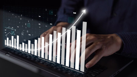 A professional person typing on a laptop with an overlay of data visualization showing financial...