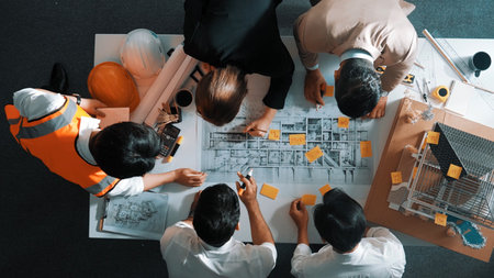 Top down view of skilled engineer team talking about house construction. Aerial view of group of architect or designer discussing and writing sticky note to brainstorm about blueprint.の写真素材