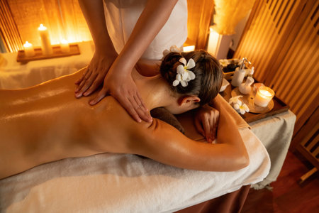 Caucasian woman customer enjoying relaxing anti-stress spa massage and pampering with beauty skin recreation leisure in warm candle lighting ambient salon spa at luxury resort or hotel. Quiescentの写真素材