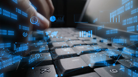 This image shows a close-up of hands typing on a laptop keyboard with digital graphs and data...