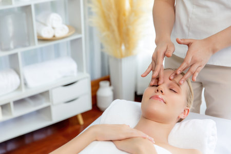 Caucasian woman enjoying relaxing anti-stress head massage and pampering facial beauty skin recreation leisure in dayspa modern light ambient at luxury resort or hotel spa salon. Quiescentの写真素材