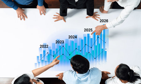 A business team collaborates around a table, analyzing a graph that illustrates annual growth projections from 2022 to 2026, showcasing strategic planning and teamwork.の写真素材