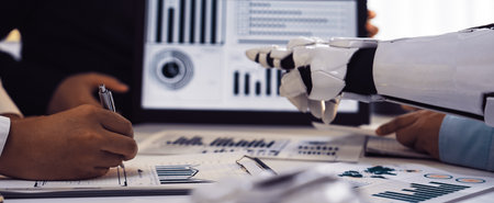 A dynamic business meeting showcases a robot assistant engaging with professionals in a modern office, presenting detailed data analysis and reports effectively.の写真素材